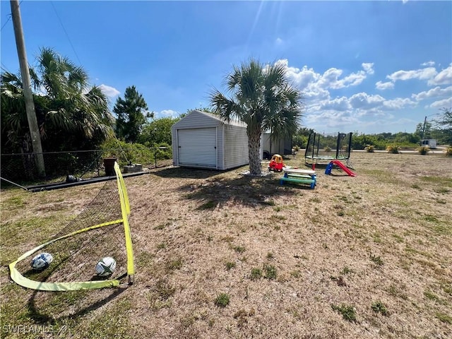 view of yard featuring a storage shed, fence, an outbuilding, and a trampoline