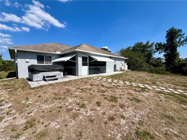 back of house with a hot tub, a patio, fence, and stucco siding