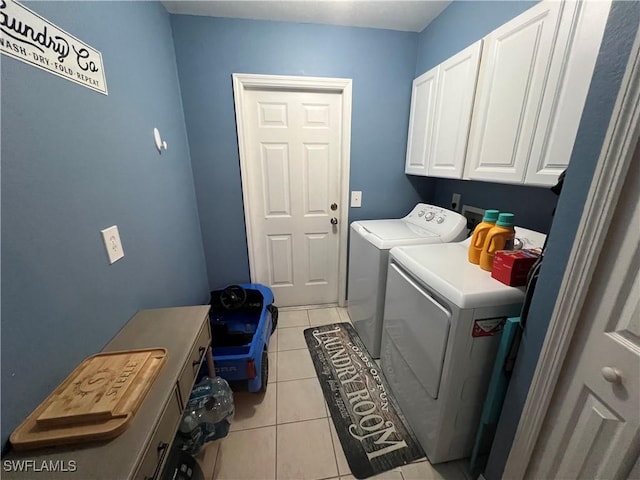 laundry area with cabinet space, light tile patterned floors, and washer and clothes dryer