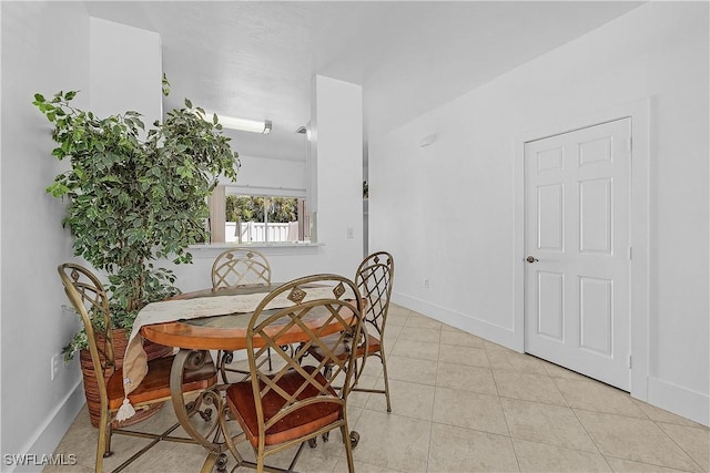 tiled dining space featuring baseboards