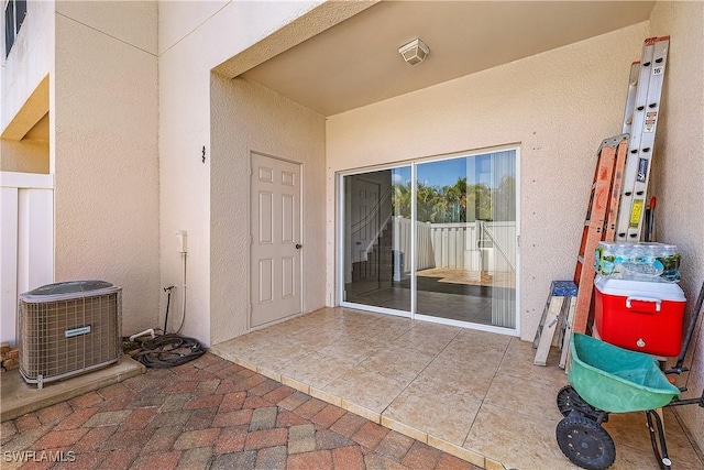 doorway to property with stucco siding, a patio area, and central air condition unit