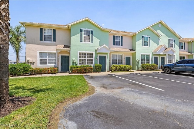 multi unit property featuring uncovered parking, a front lawn, and stucco siding