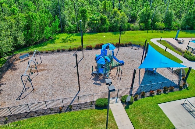 view of property's community featuring a lawn, fence, and playground community