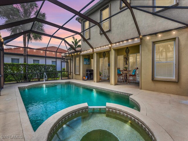 12156 Ledgewood Cir, Fort Myers, FL 33913 - pool at dusk with a patio area, glass enclosure, and a pool with connected hot tub