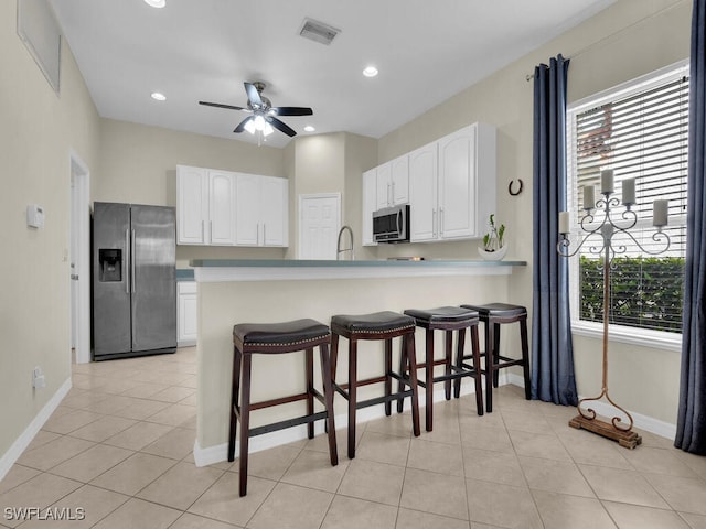 12156 Ledgewood Cir, Fort Myers, FL 33913 - kitchen with a breakfast bar, white cabinetry, visible vents, baseboards, and appliances with stainless steel finishes