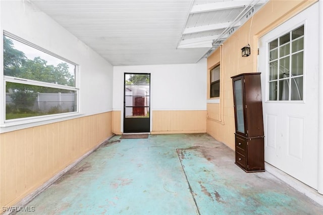 empty room with wooden walls, wainscoting, and concrete floors