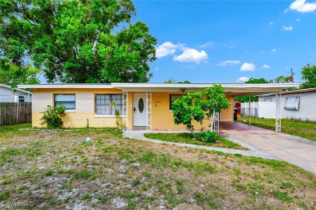 ranch-style house with brick siding, fence, driveway, and a carport