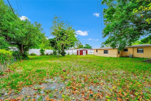 view of yard featuring an outdoor structure, fence, and a storage shed
