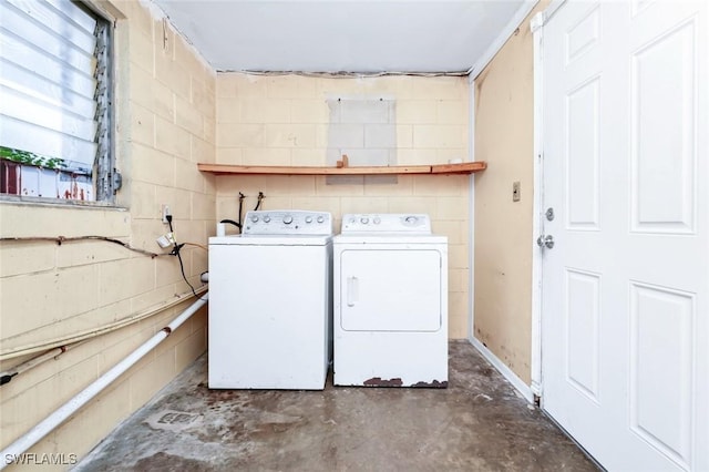clothes washing area with washer and dryer, concrete block wall, and laundry area
