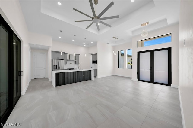 unfurnished living room featuring baseboards, recessed lighting, a raised ceiling, french doors, and a ceiling fan