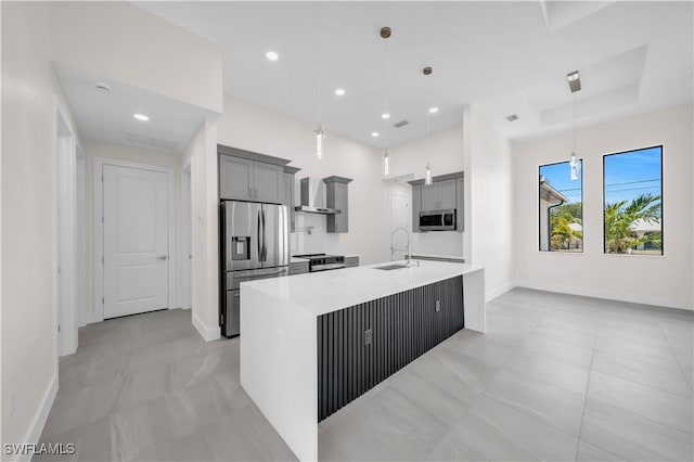 kitchen featuring wall chimney range hood, appliances with stainless steel finishes, a sink, baseboards, and gray cabinetry