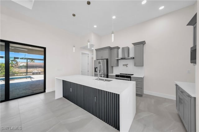 kitchen with light countertops, gray cabinets, wall chimney exhaust hood, stainless steel appliances, and pendant lighting