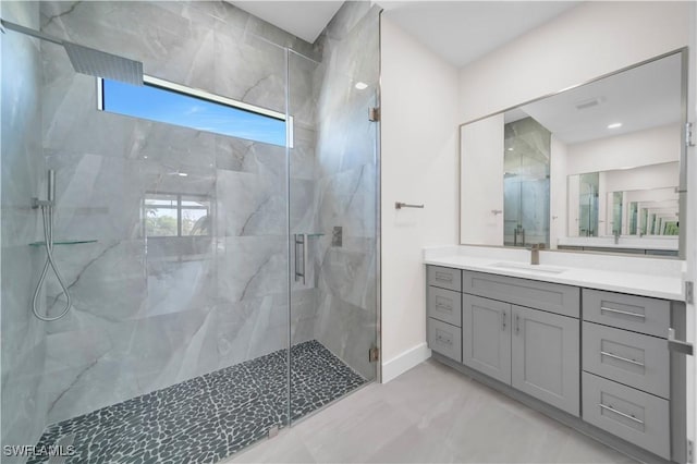 full bath featuring baseboards, a marble finish shower, marble finish floor, and vanity