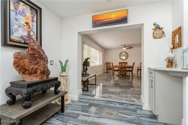hallway featuring baseboards, a sink, and marble finish floor