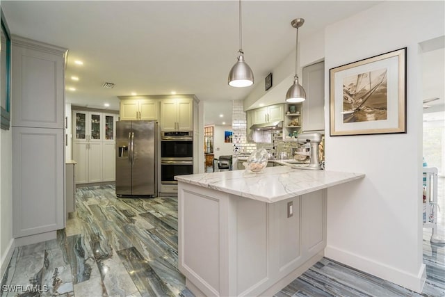 kitchen featuring a peninsula, tasteful backsplash, light stone counters, hanging light fixtures, and stainless steel appliances