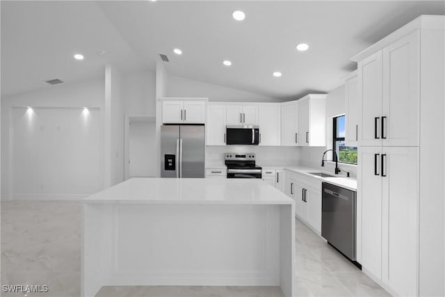 kitchen featuring lofted ceiling, a center island, white cabinetry, a sink, and stainless steel appliances
