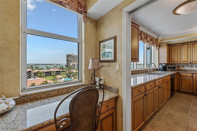 kitchen featuring brown cabinets, light stone counters, a sink, tile patterned floors, and black dishwasher