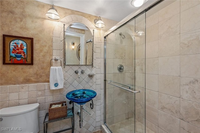 bathroom featuring tile walls, a shower stall, and toilet