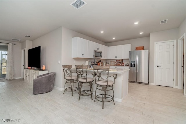kitchen featuring a breakfast bar area, stainless steel appliances, a peninsula, and visible vents