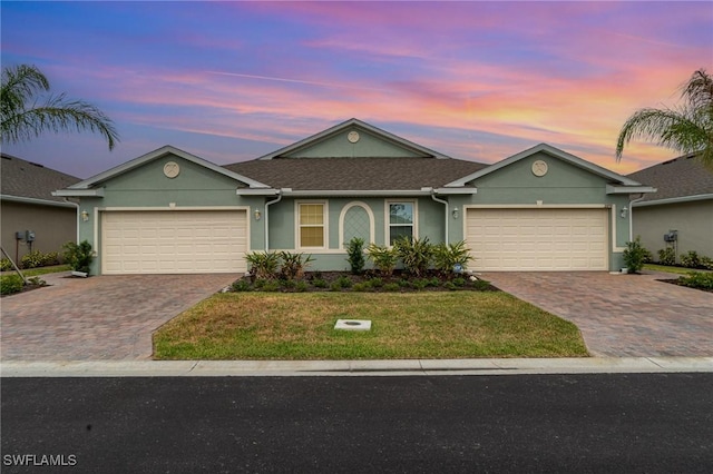 ranch-style house with decorative driveway, an attached garage, and stucco siding
