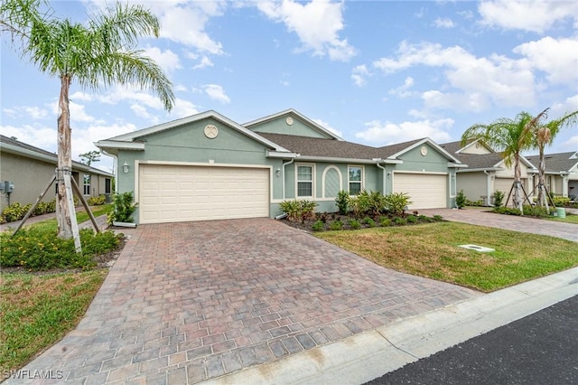 single story home with decorative driveway, a garage, stucco siding, and a front yard