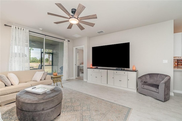 living area featuring baseboards, a ceiling fan, light wood-style flooring, and visible vents