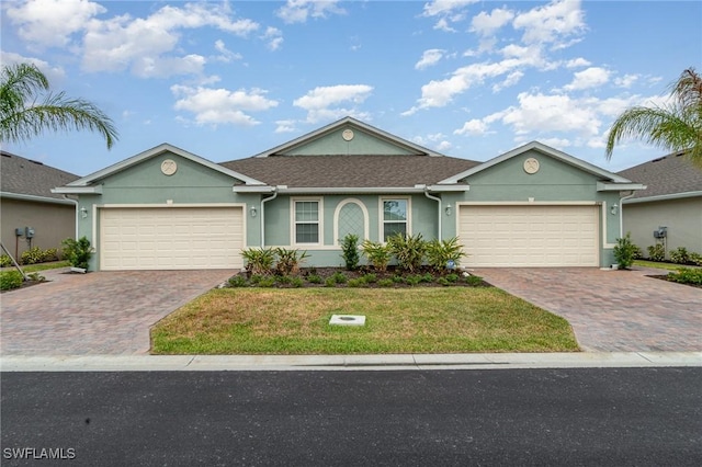single story home with an attached garage, decorative driveway, and stucco siding