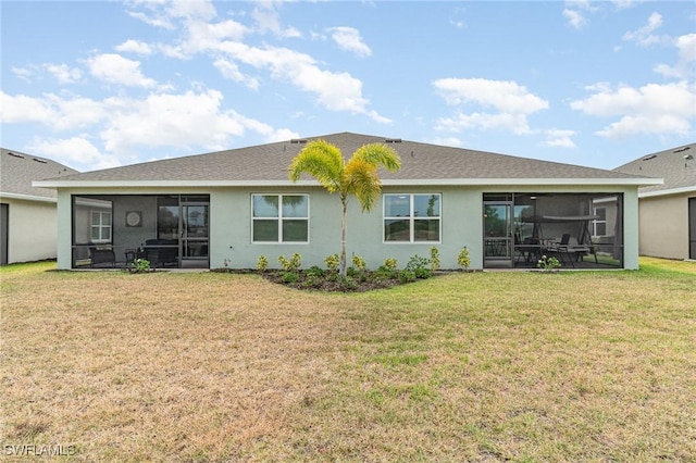 rear view of property featuring a lawn, stucco siding, and a sunroom