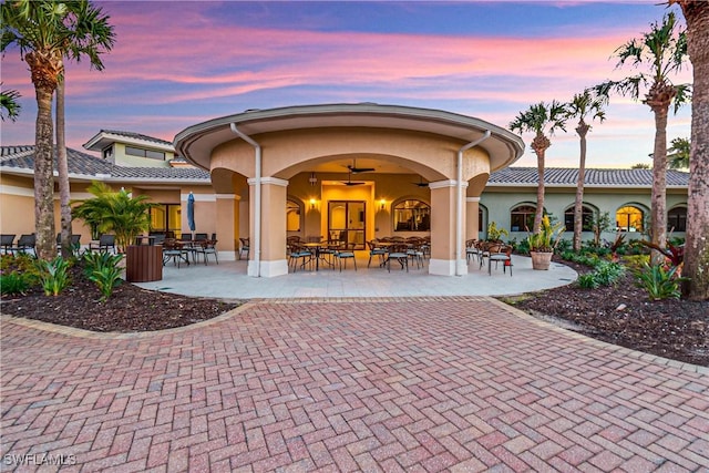 10419 Materita Dr, Fort Myers, FL 33913 - back of house at dusk featuring stucco siding, outdoor dining space, and a patio