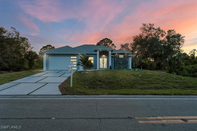 view of front of house featuring a lawn, a garage, stucco siding, and concrete driveway