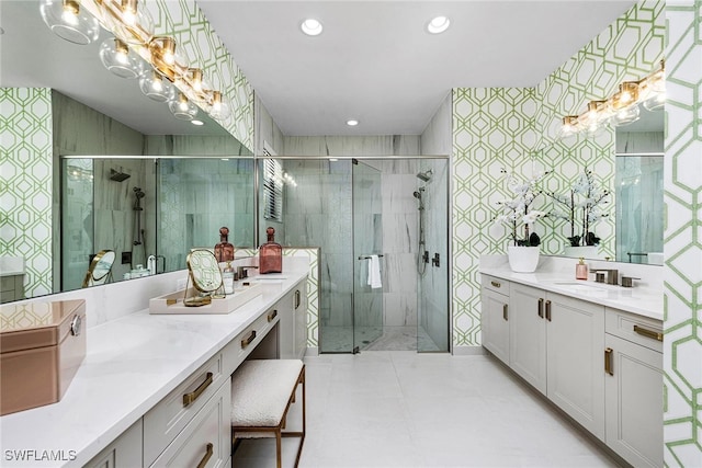 bathroom with an inviting chandelier, wallpapered walls, tile walls, two vanities, and a stall shower