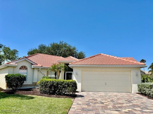 1106 Islamorada Blvd, Punta Gorda, FL 33955 - mediterranean / spanish home with stucco siding, a tile roof, decorative driveway, a garage, and a front yard