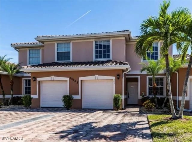view of front of home featuring a garage, stucco siding, a tile roof, and decorative driveway