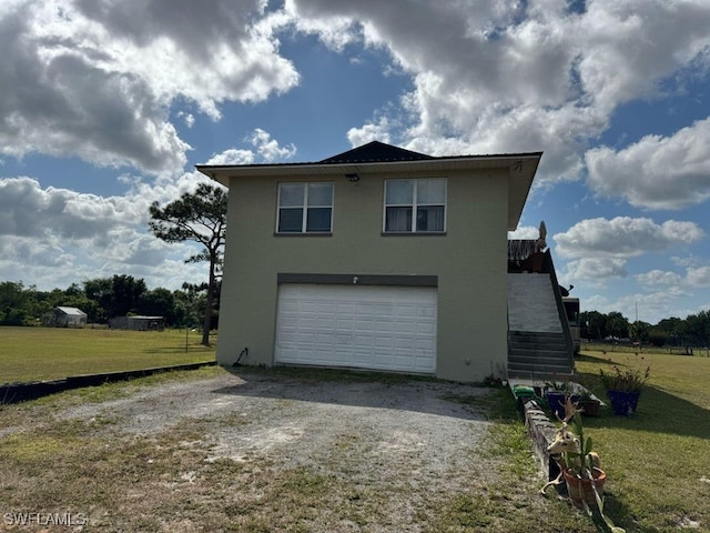 view of side of property featuring a garage, stucco siding, a lawn, and driveway