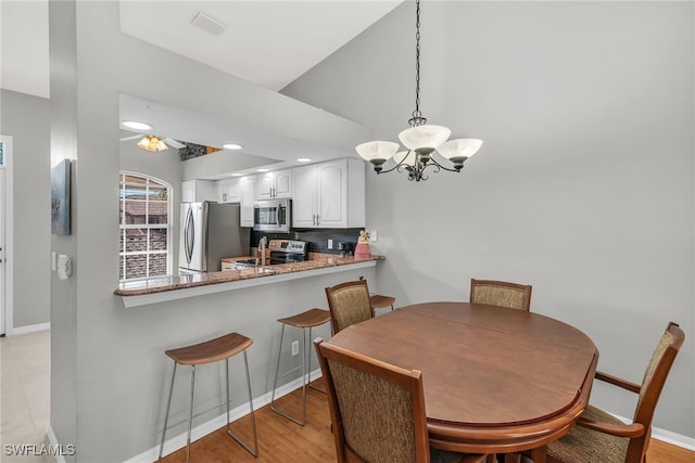 162 Newport Dr Unit 1208, Naples, FL 34114 - dining area with baseboards, visible vents, lofted ceiling, and a notable chandelier