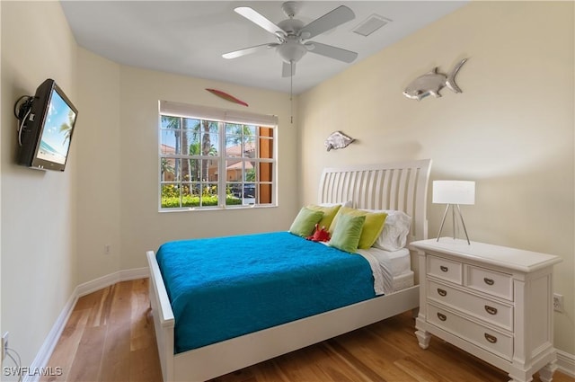 bedroom with a ceiling fan, baseboards, visible vents, and wood finished floors