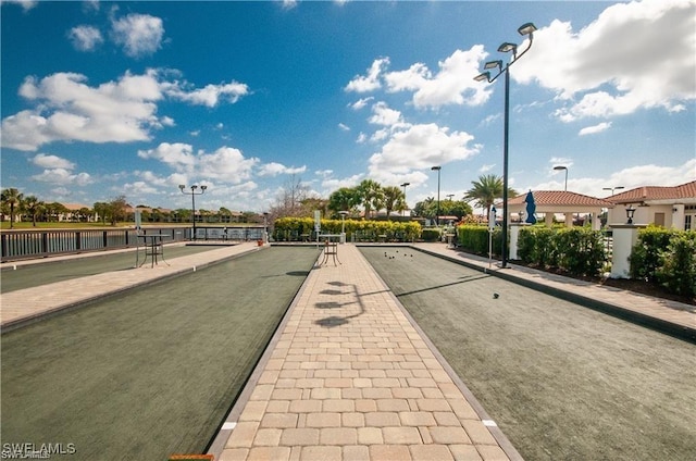 view of road featuring street lighting, curbs, a gated entry, and sidewalks