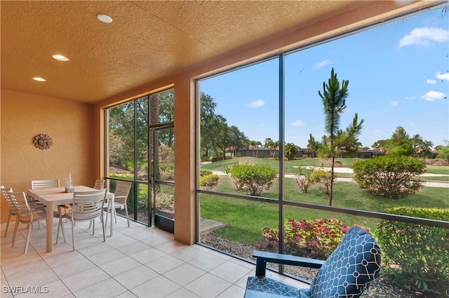 sunroom with a textured wall, outdoor dining space, recessed lighting, a textured ceiling, and tile patterned floors