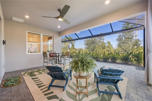 view of patio featuring a lanai, a ceiling fan, outdoor dining area, and visible vents