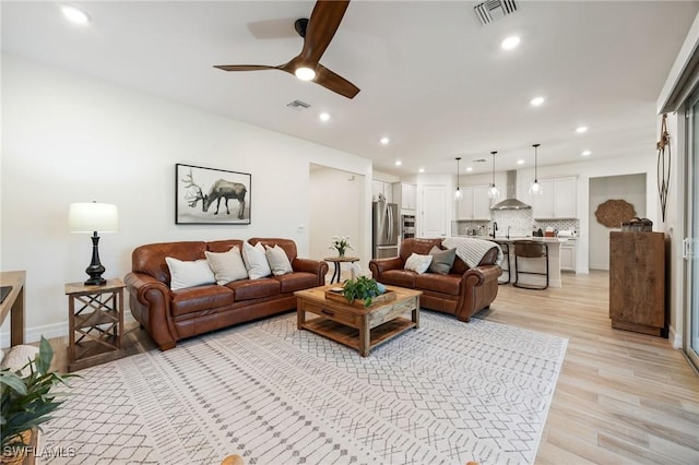 living room featuring a ceiling fan, recessed lighting, light wood-style flooring, and visible vents