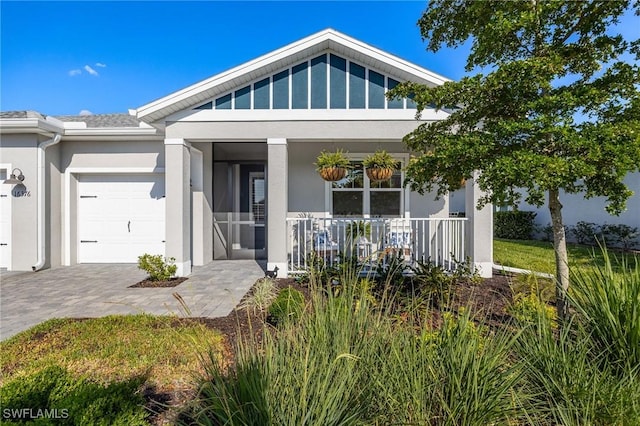 view of front facade with a porch, an attached garage, driveway, and stucco siding