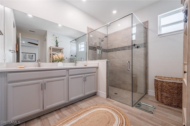 full bathroom featuring recessed lighting, double vanity, wood finished floors, and a shower stall