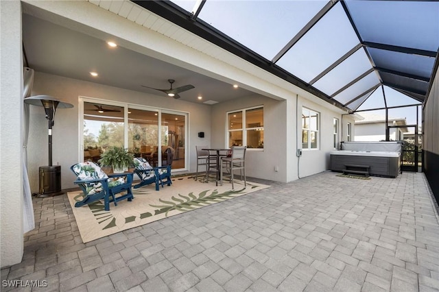 view of patio featuring a hot tub, a ceiling fan, outdoor dining space, and glass enclosure