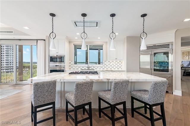 4931 Bonita Bay Blvd Unit 601, Bonita Springs, FL 34134 - kitchen featuring visible vents, decorative backsplash, a kitchen island, white cabinets, and appliances with stainless steel finishes