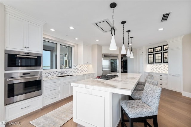 4931 Bonita Bay Blvd Unit 601, Bonita Springs, FL 34134 - kitchen featuring backsplash, appliances with stainless steel finishes, a center island, a sink, and white cabinetry
