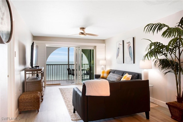 living area with baseboards, a ceiling fan, and wood finished floors
