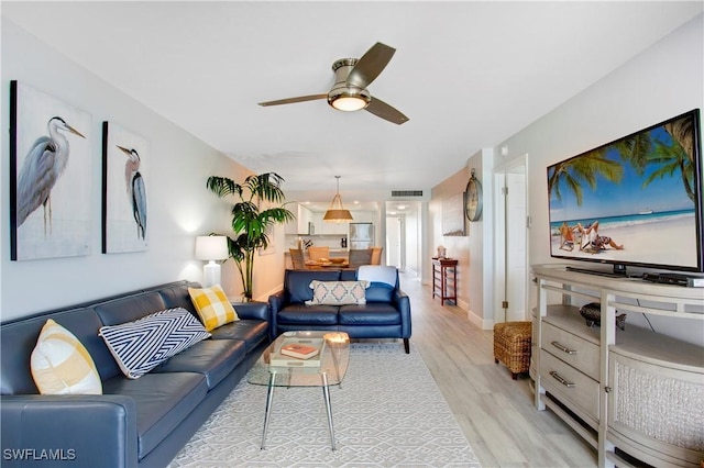 living room with baseboards, a ceiling fan, light wood-type flooring, and visible vents