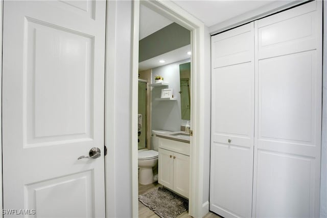 full bathroom with toilet, a shower with door, wood finished floors, and vanity
