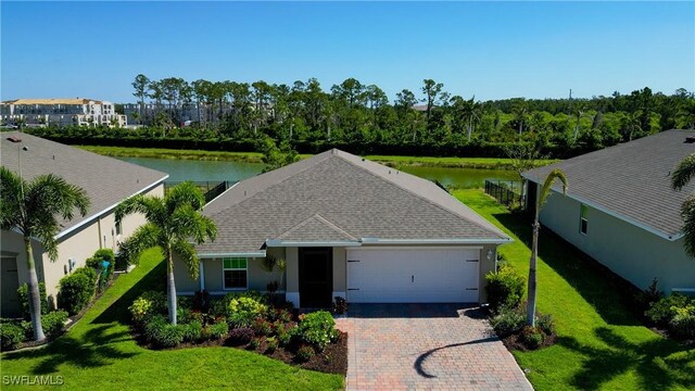 ranch-style home with a front yard, a garage, decorative driveway, a water view, and a shingled roof