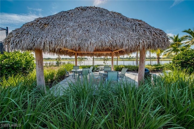 exterior space with a gazebo, a water view, fence, and a patio